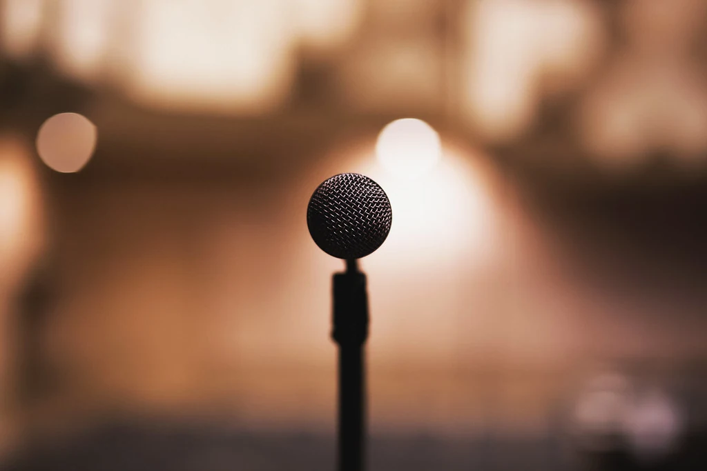 A black microphone on a stand against a softly blurred amber background