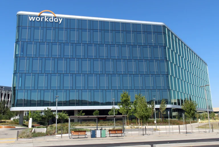 Workday lettering on a glass office building beneath a clear blue sky in Pleasanton.