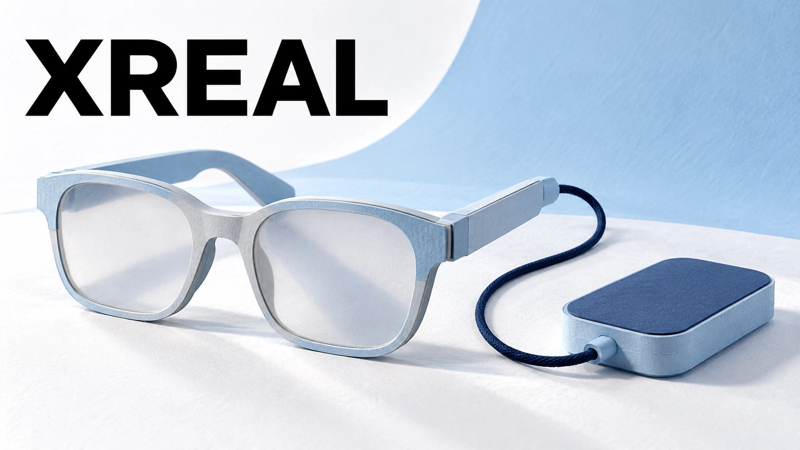 XREAL wordmark above pale blue paper glasses linked by a navy cord to a rounded rectangular companion block.